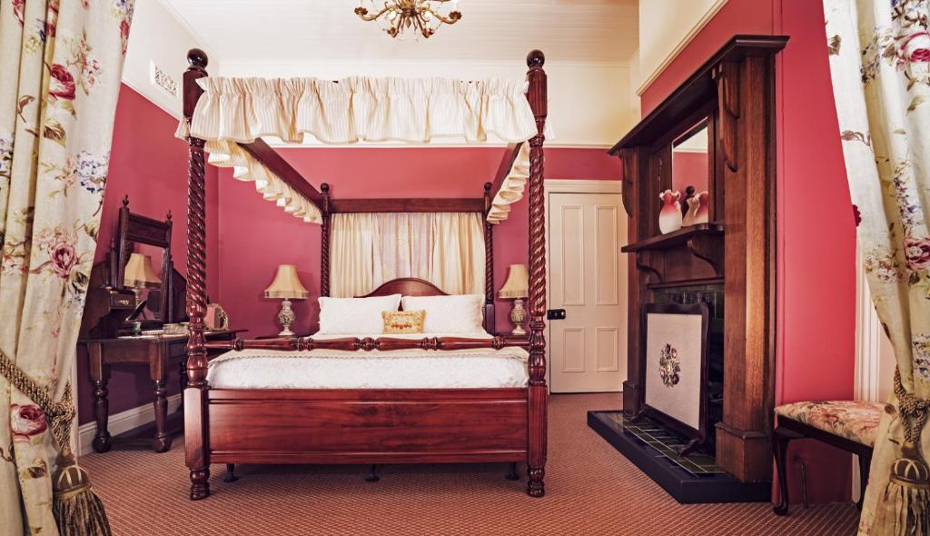 肯图巴库拉拉历史旅馆的一间卧室设有一张天蓬床和一个壁炉