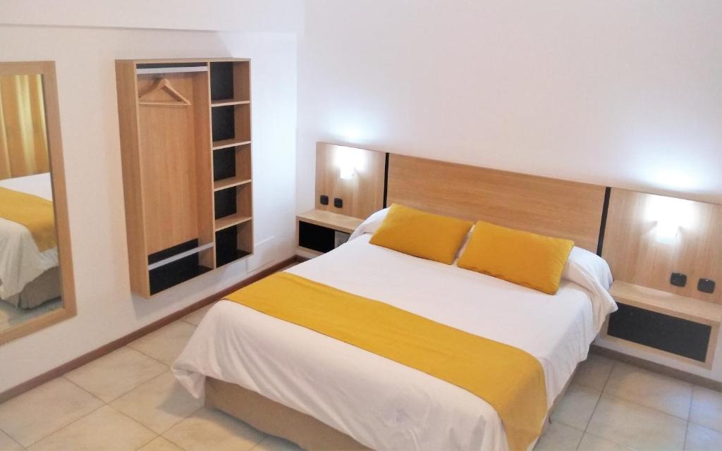 门多萨Apartamentos Mendoza的一间卧室配有一张带黄色枕头的大床