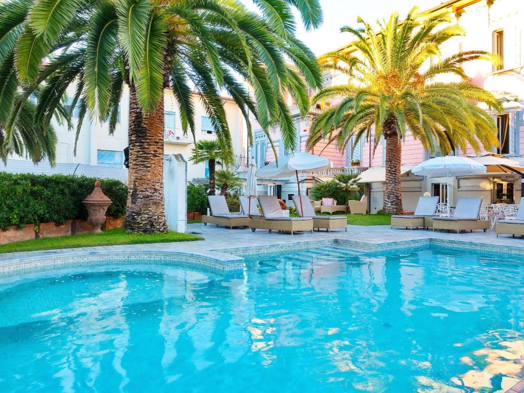 利多迪卡马约雷欧洲大酒店 的一座棕榈树和椅子的游泳池以及一座建筑