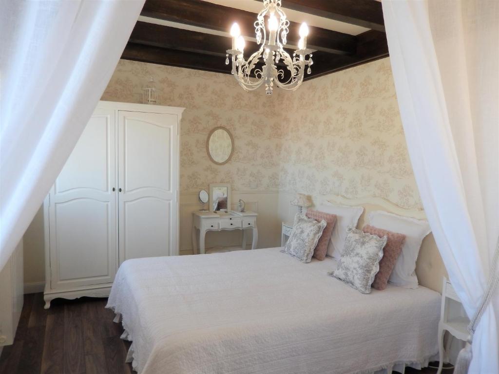 Réau拉科多讷瑞德利奥旅馆的卧室配有白色的床和吊灯。