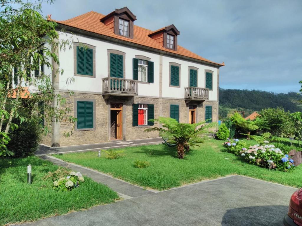 莫尼兹港Quinta do Serrado的一座带绿色百叶窗和庭院的大房子