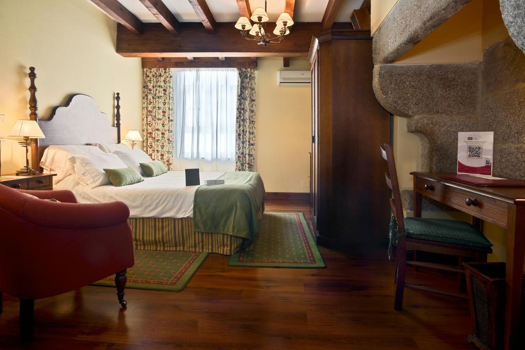 圣地亚哥－德孔波斯特拉Airas Nunes by Pousadas de Compostela的一间卧室配有一张床、一张书桌和一个窗户。