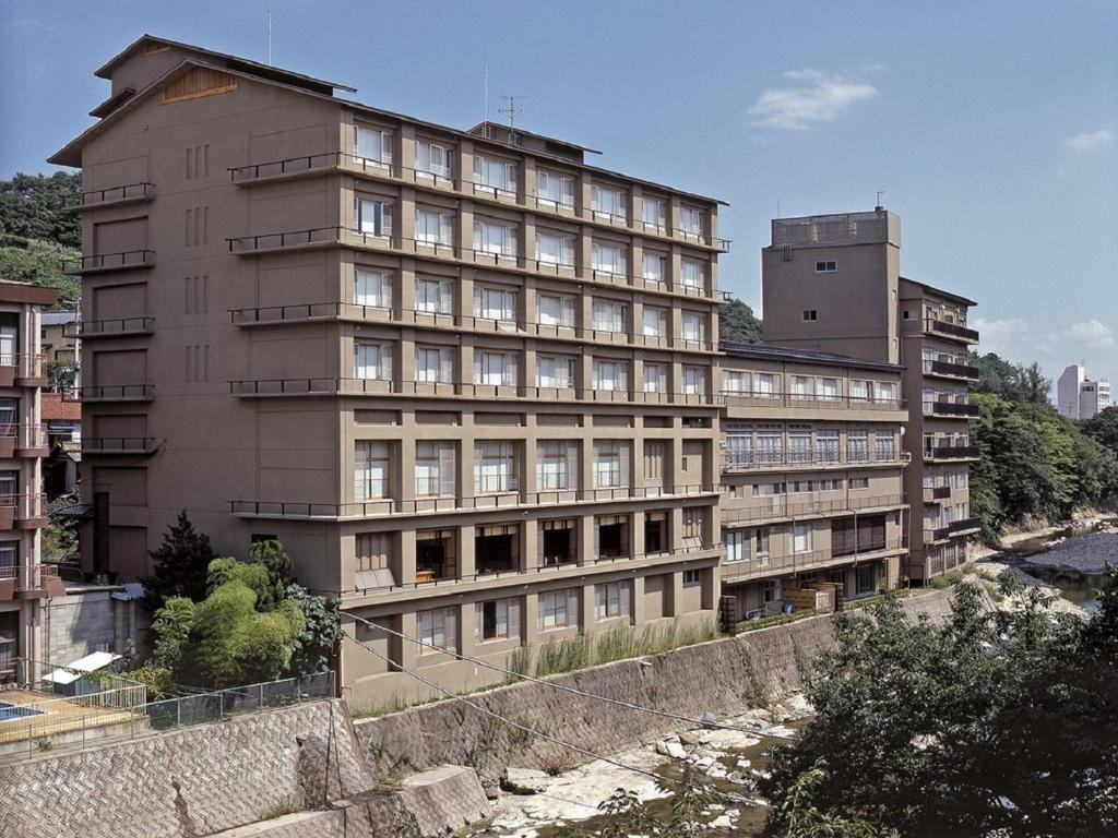 福岛Itoen Hotel Iizakakanouya的一座高大的建筑,毗邻一条有建筑物的河流