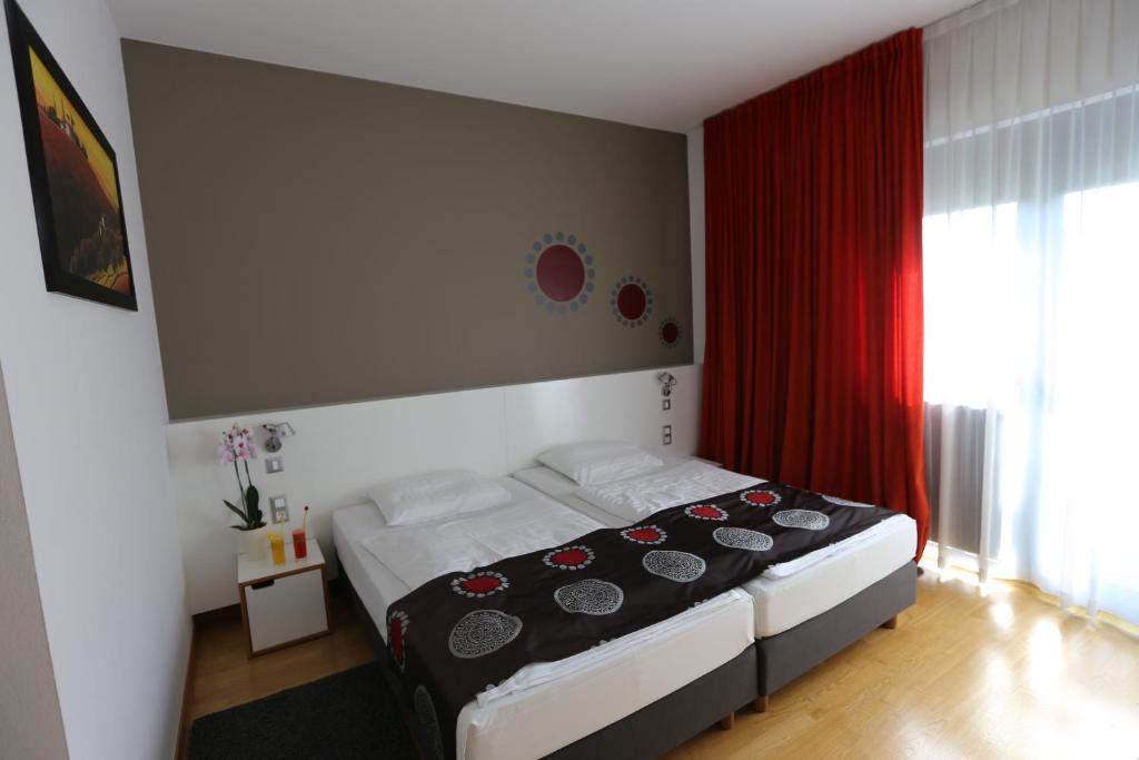 Draganići德拉甘尼克酒店的一间卧室配有一张带红色窗帘的床