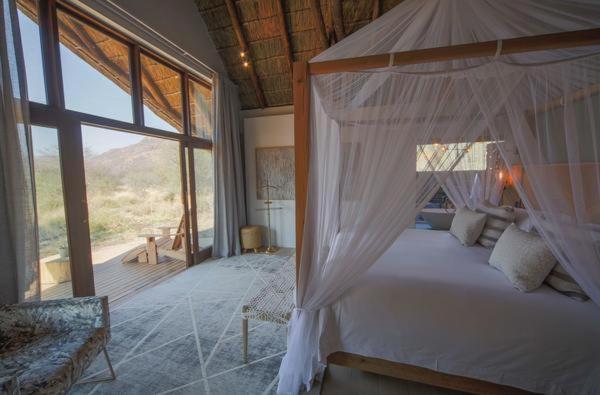 MatlhagameNkala Safari Lodge的一间卧室设有一张天蓬床和大窗户