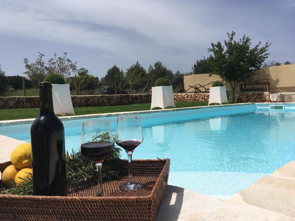 锡内乌Sa Estada的游泳池旁的一瓶葡萄酒和两杯酒