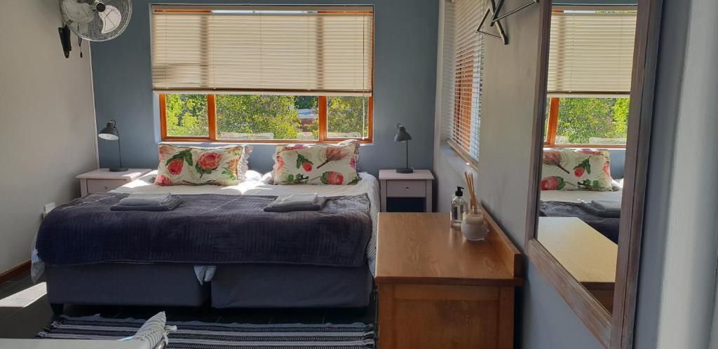 斯泰伦博斯Cobie Apartment的一间卧室配有一张床、一张书桌和两个窗户。