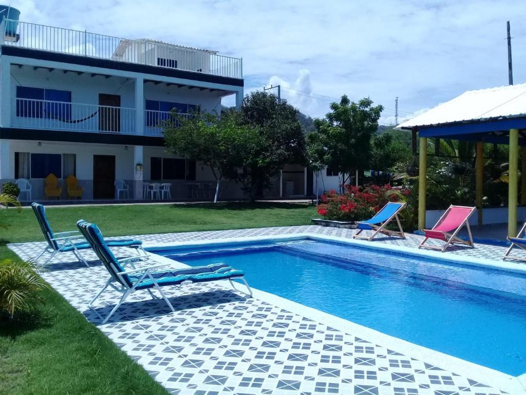 TubaráCasa de Campo Palmarito的一个带两把椅子的游泳池以及一座房子