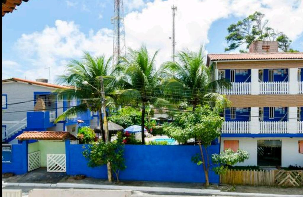 嘎林海斯港Chalés Caiçara Serrambi的一座蓝色的建筑,前面有棕榈树