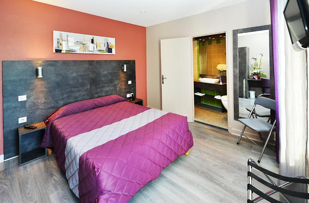 罗德兹Hôtel Concorde - Rodez Centre Ville的一间卧室配有一张大床和紫色毯子