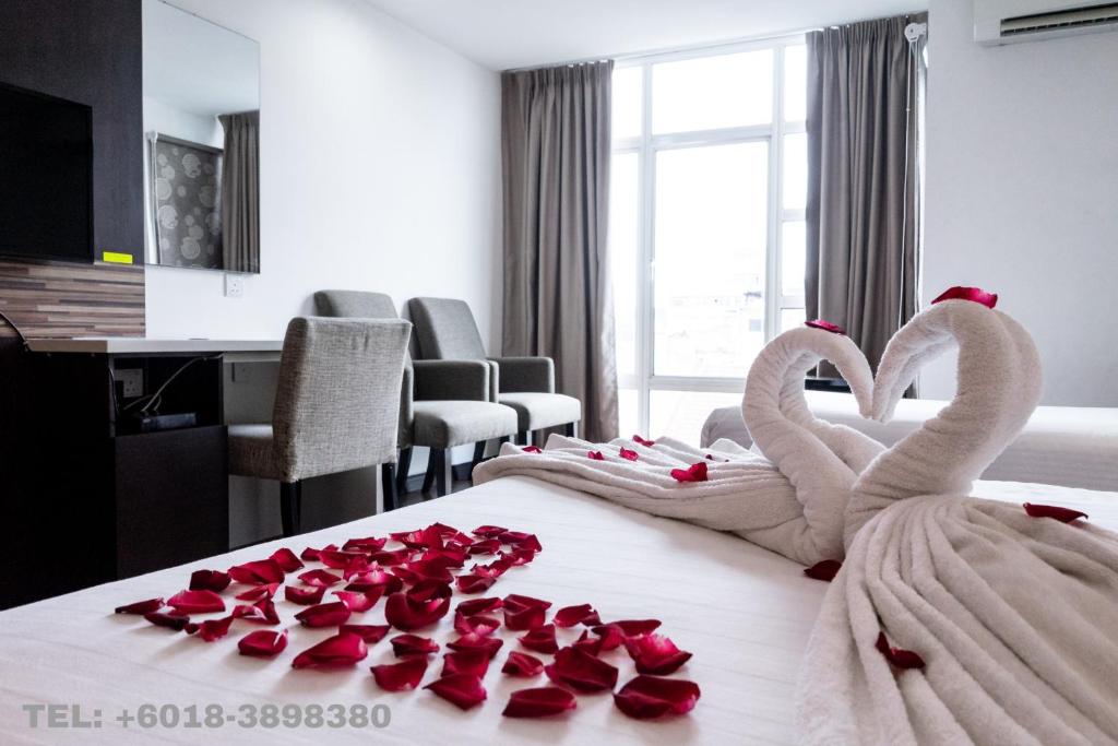 哥打巴鲁Classy Studio Apartment (KBCP)的两个天鹅在床上,上面有玫瑰花