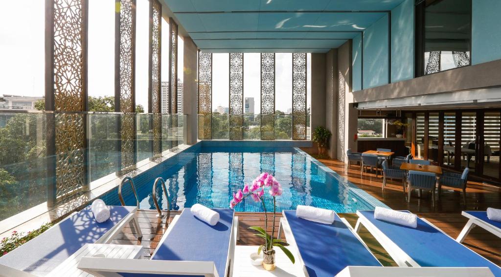 胡志明市兰花西贡酒店的大楼内带蓝色椅子的大型游泳池