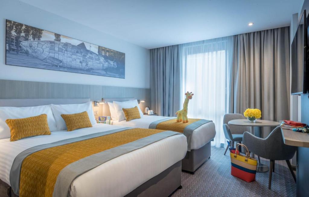 科克Maldron Hotel South Mall Cork City的酒店客房设有两张床,床上有玩具长颈鹿