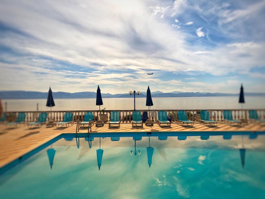 GastouriBrentanos Apartments - A - View of Paradise的游泳池配有椅子、遮阳伞和水