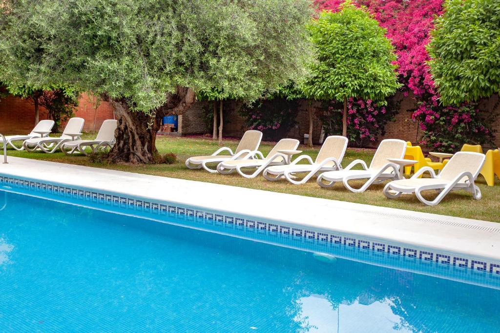 塞维利亚AACR蒙蒂奥里维斯酒店的一组躺椅,位于游泳池旁
