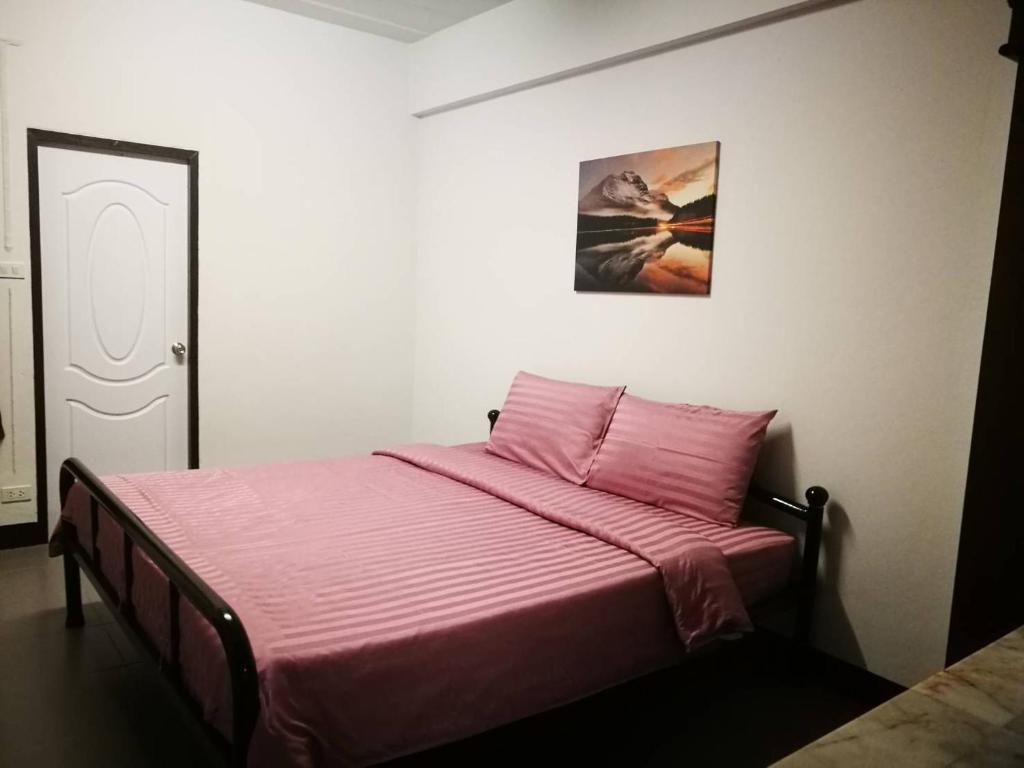 清迈Duangdren Apartment的一间卧室配有一张带粉色毯子的床