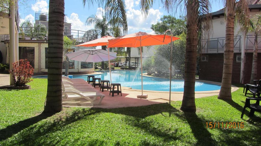 费德拉西翁Paraiso Termal的游泳池配有两把遮阳伞、椅子和桌椅