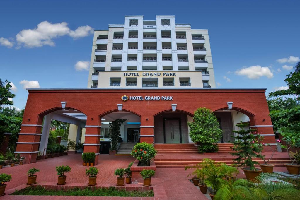 巴里沙尔Hotel Grand Park Barishal的一座红砖建筑,后面是一座高大的建筑