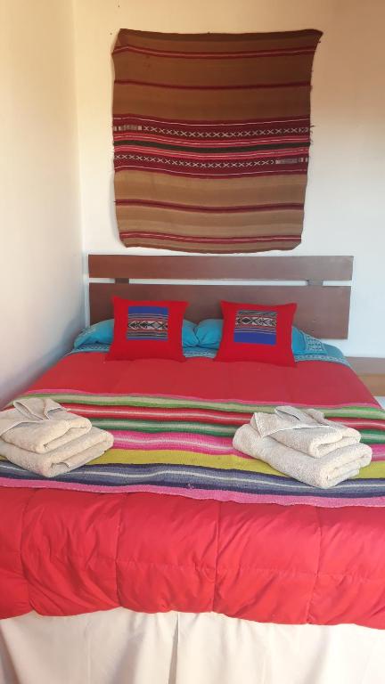 圣佩德罗·德·阿塔卡马Hostal Open House的红色的床,上面有红色的枕头和毛巾