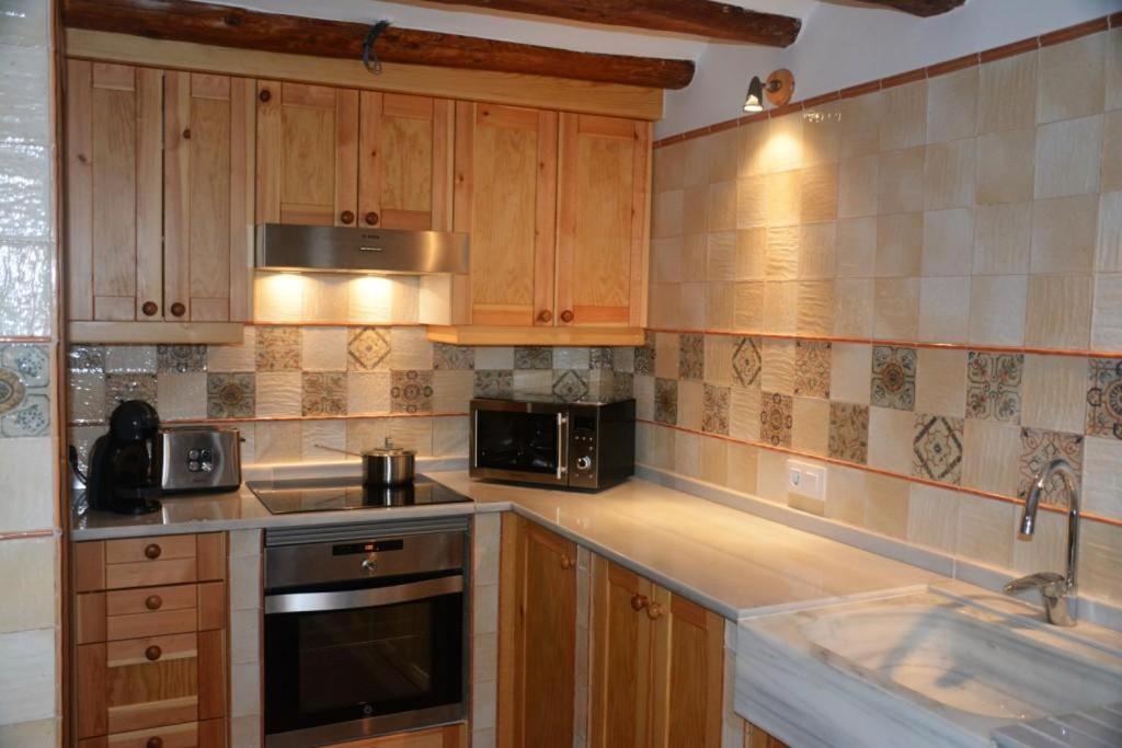 El VilosellCal Triquell的厨房配有木制橱柜和炉灶烤箱。