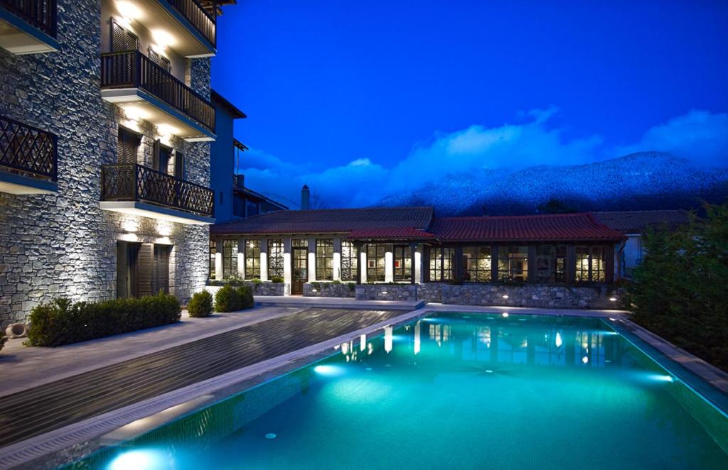 维蒂纳Art Mainalon Hotel的一座游泳池,在晚上在建筑物前