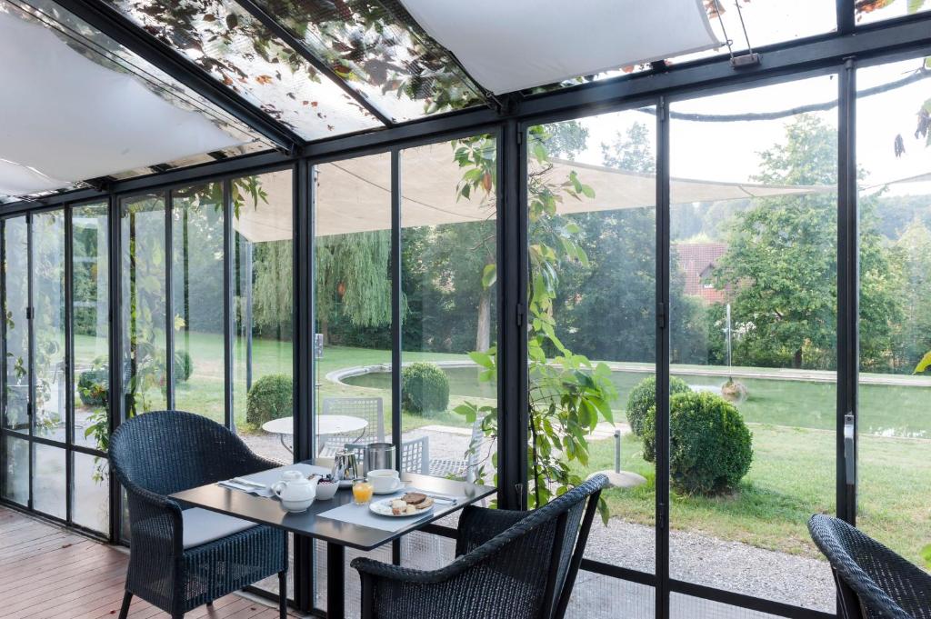 穆尔滕宫明兴维勒酒店的一个带桌椅和玻璃门的温室