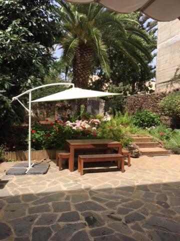 拉拉古纳Casa Del Casco Historico的花园里的野餐桌和遮阳伞