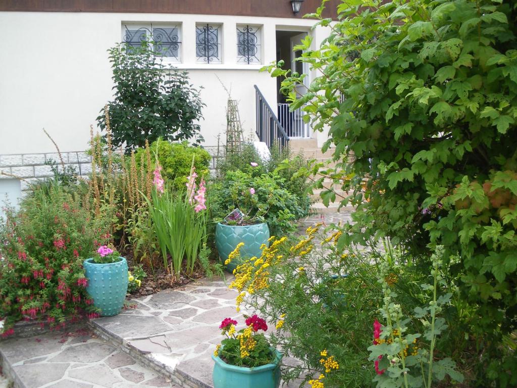 VernouilletChambre d'Hôtes - DOUCE NUI-THE的一座花园,里面种有鲜花和水桶里的植物