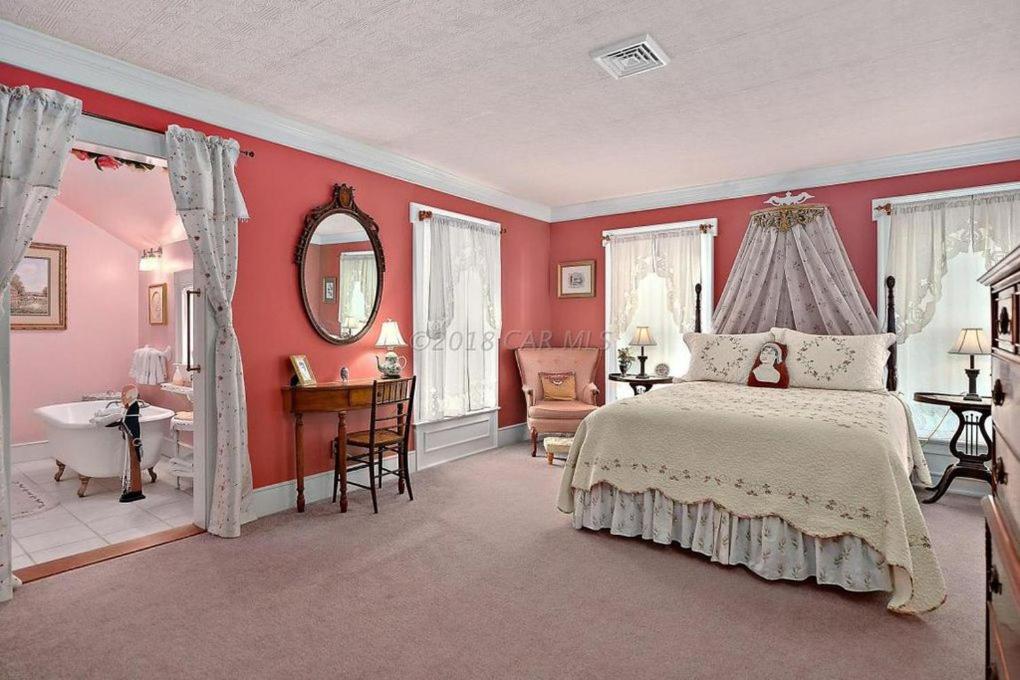 Princess AnnePrincess Anne Book Lovers Inn的一间卧室设有粉红色的墙壁、一张床和一间浴室