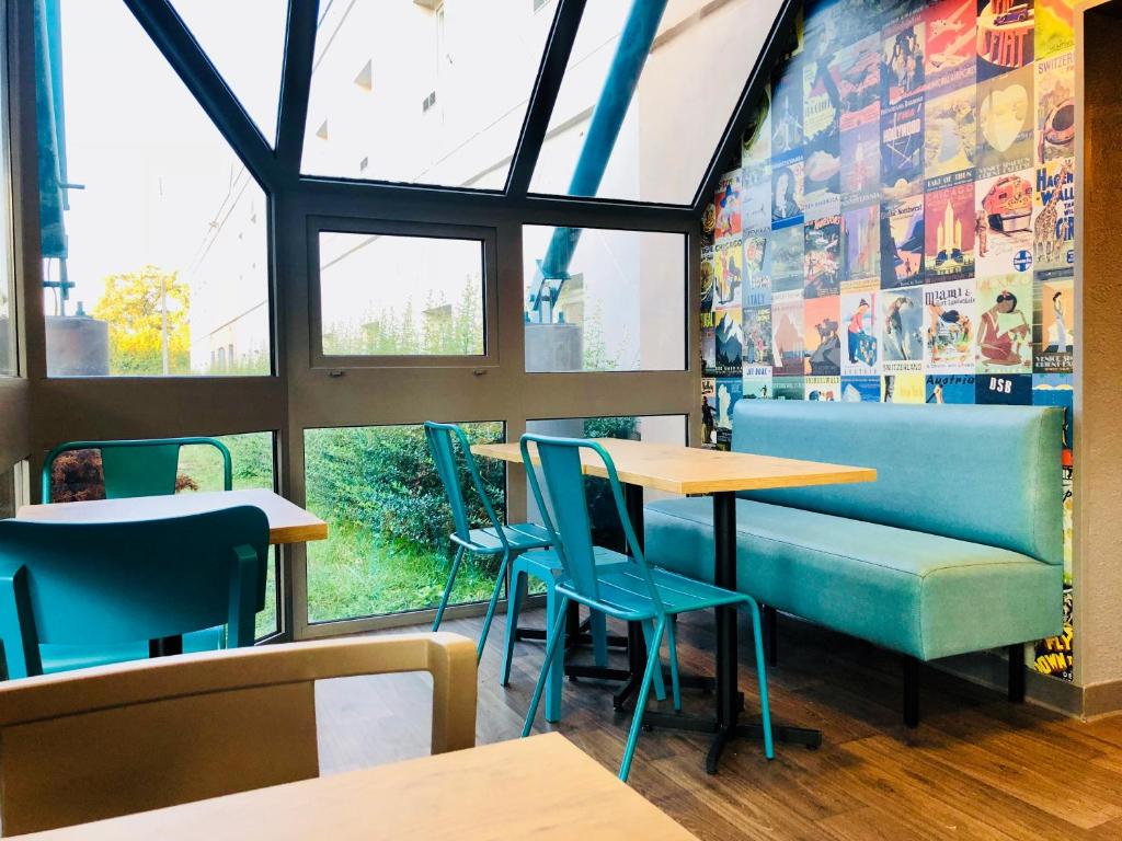费内-伏尔泰hotelF1 Genève Aéroport Ferney的餐厅设有蓝色的桌椅和窗户。