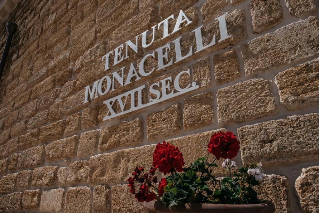 莱切Tenuta Monacelli Lecce的砖墙上的一个标志,花在锅里