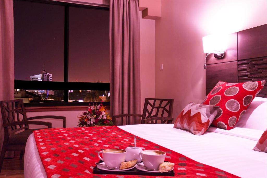 内罗毕比德伍德套房酒店 的一间酒店客房,配有一张床铺,上面放着一个食物托盘