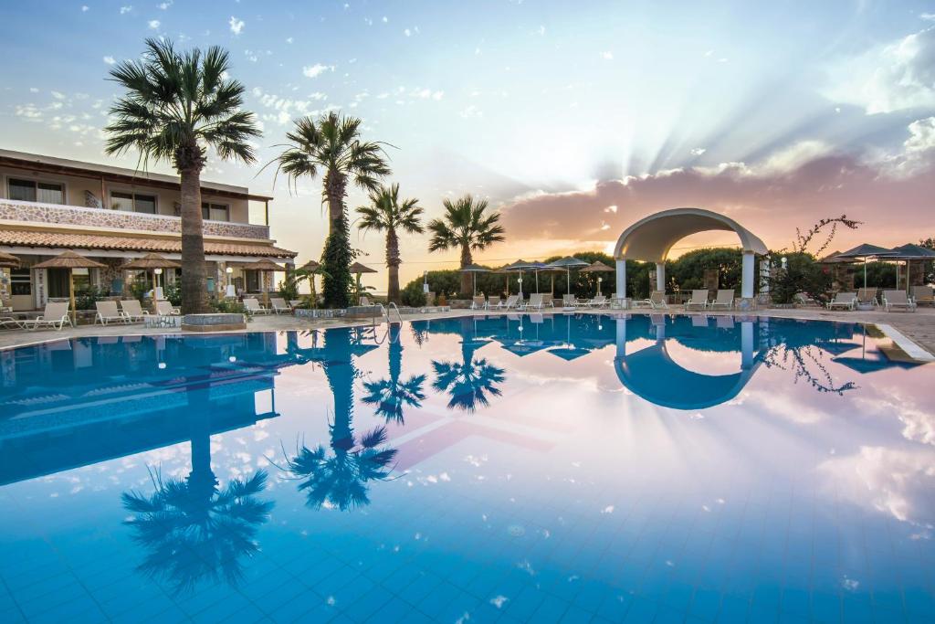 马斯蒂查里Kouros Palace的棕榈树和日落度假村的游泳池