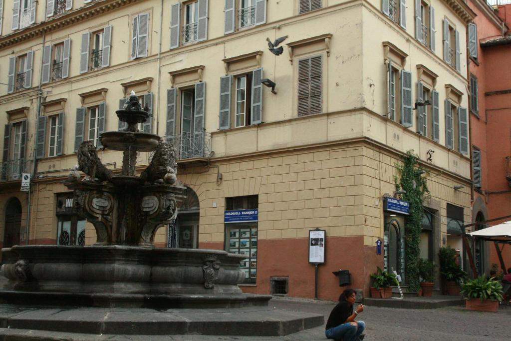 维泰博安蒂科安杰洛-埃波卡旅馆 的坐在喷泉旁的建筑物前的女人