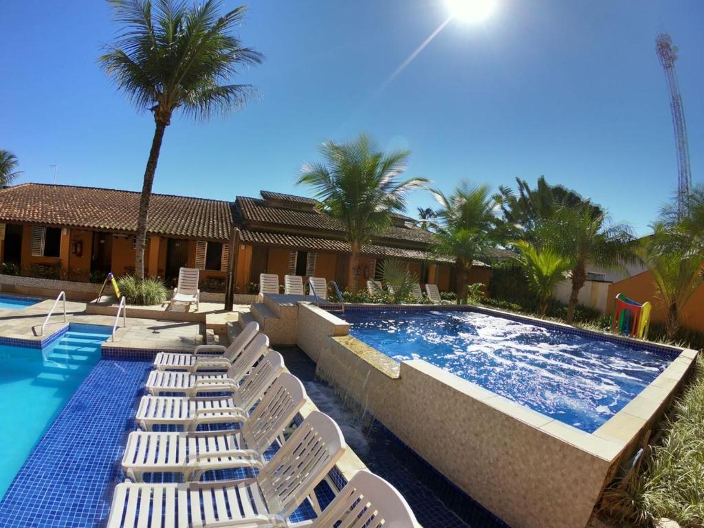 伯迪亚哥Pousada Costa da Riviera的一个带白色躺椅的游泳池和一个游泳池