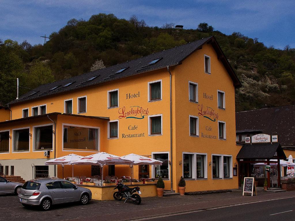 圣戈阿尔诺里布里克咖啡厅酒店的一座黄色的大建筑,前面有汽车停放