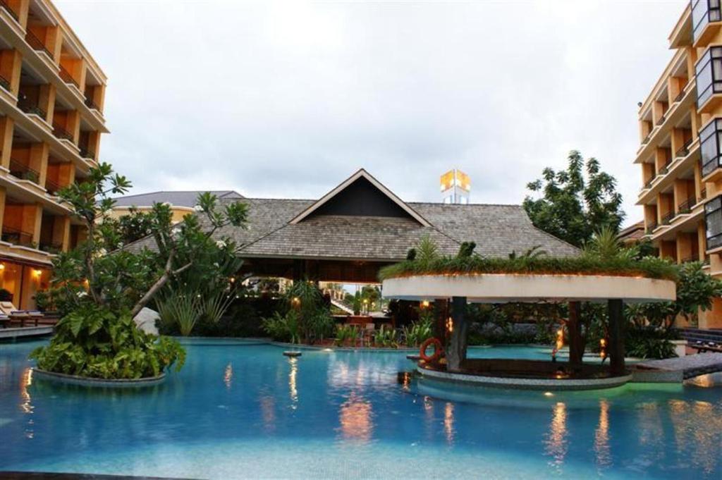 芭堤雅市中心LK Mantra Pura Resort的一座带树木和建筑的游泳池的度假村