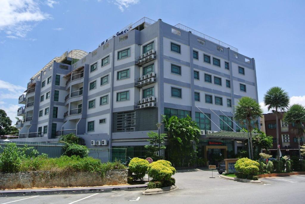 瓜拉比拉Melang Inn的停车场内种植植物的大型白色建筑