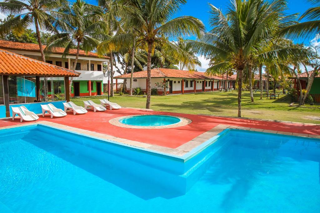 塞古罗港Pousada Morada dos Coqueiros的一个带椅子的游泳池,一个度假胜地