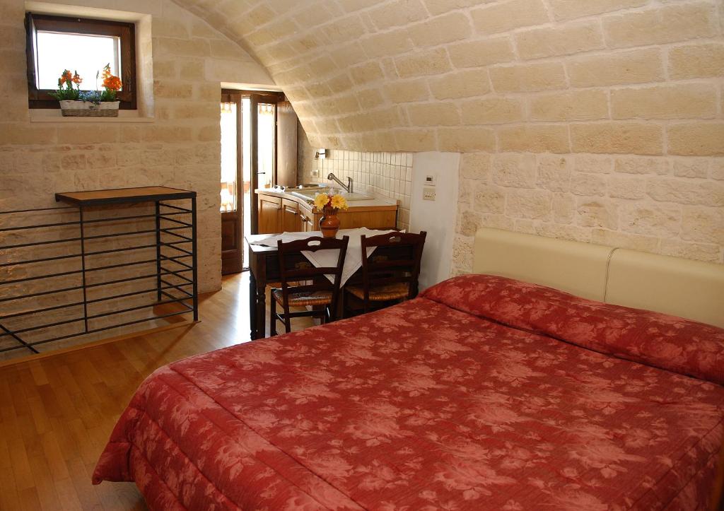 阿尔贝罗贝洛特鲁利玛尼亚住宿加早餐酒店的一间带一张床和一张书桌的卧室和一间厨房