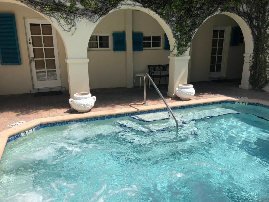 劳德代尔堡Courtyard Villa Hotel的游泳池内有两只白色花瓶