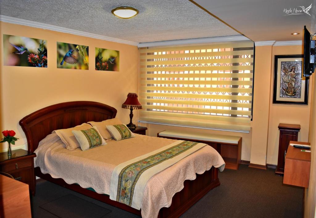 基多Kinde House的一间卧室配有一张床和一个带百叶窗的窗户