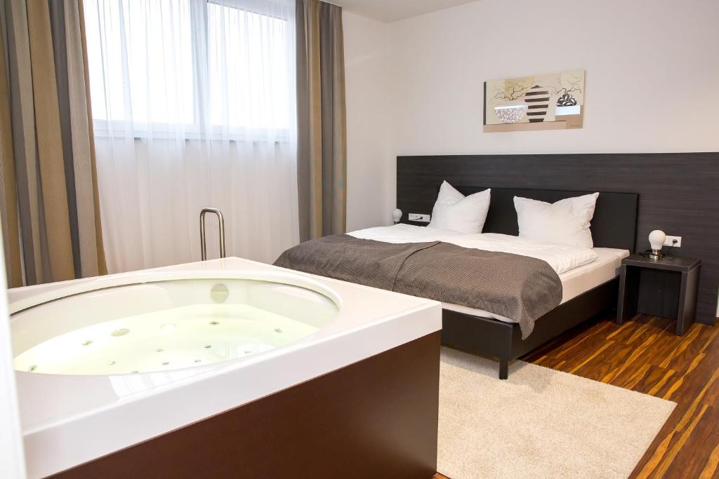韦因加尔滕Plus Punkt Private Spa的带浴缸和床的酒店客房