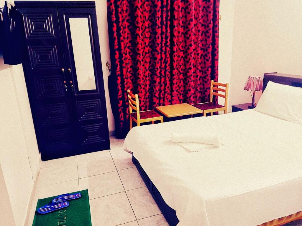 沙迦索菲亞酒店的一间卧室配有一张床,一扇门配有红色窗帘