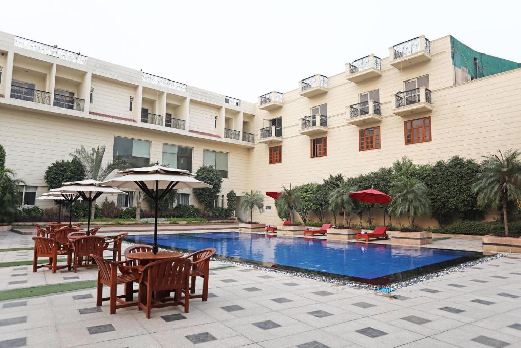 新德里Westend Inn - Resort and Banquet Near Delhi Airport的酒店设有一个游泳池和桌椅