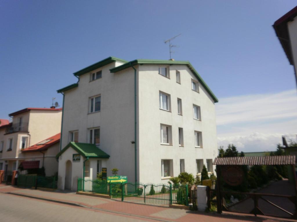 达洛科APARTAMENT i pokoje Aura Dom Wczasowy的街道上一座白色的建筑,有绿色的围栏