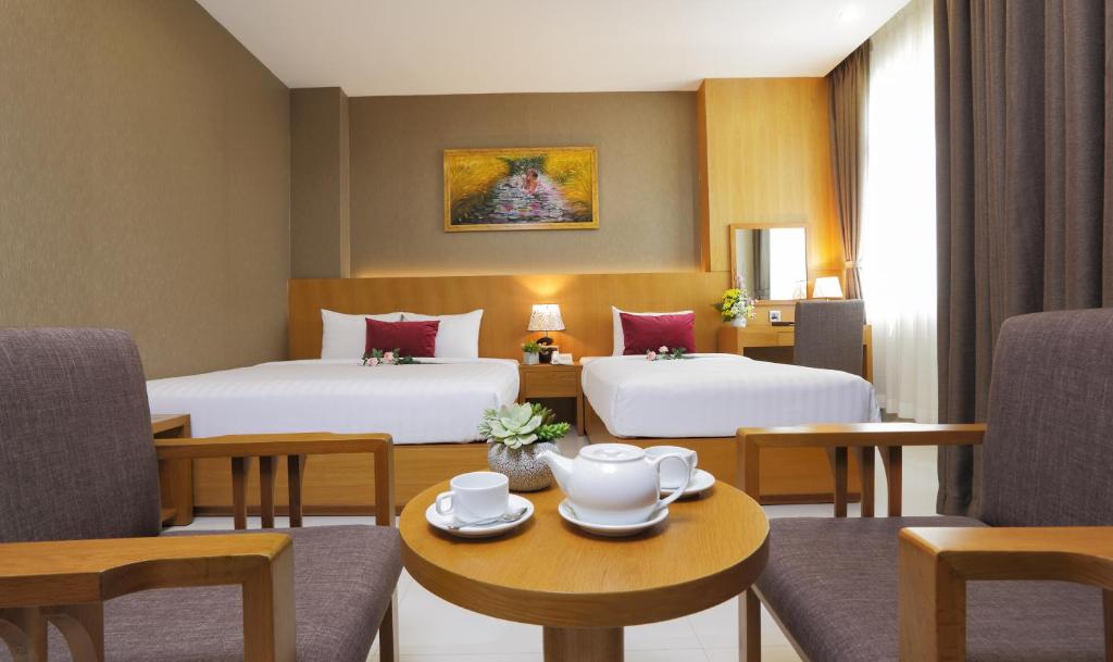 胡志明市Golda Hotel的酒店客房带两张床和一张桌子以及椅子。