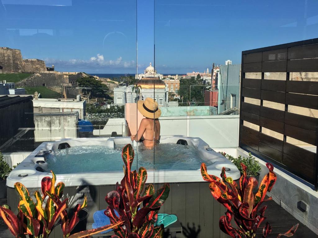 圣胡安352 Guest House Hotel Boutique的坐在一座大楼顶部的热水浴缸中的男人