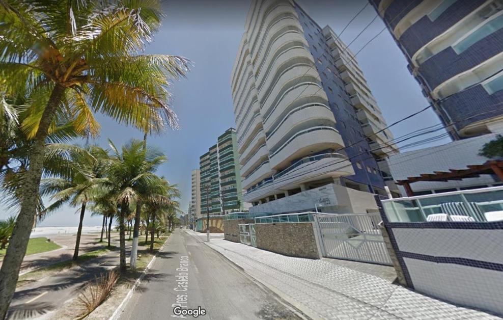 索莱马Apartamento Praia Grande Pé na areia的一条种有棕榈树的街道和一座高大的建筑