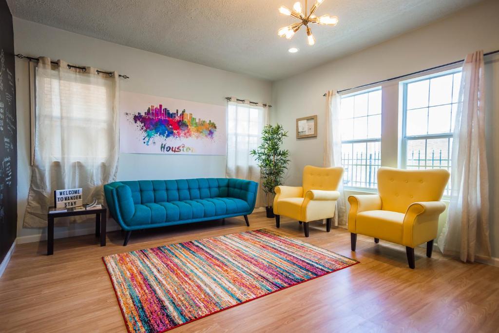 休斯顿Wanderstay Houston Hostel的客厅配有蓝色的沙发和2把黄色的椅子